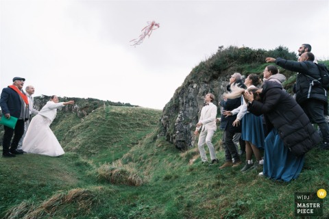   At Dunseverick Castle in Northern Ireland, the bride enthusiastically throws a tied ribbon bundle from the ceremony, while guests eagerly try to catch it, hoping to be next down the aisle.