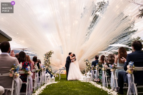   At Castello Bevilacqua in Verona, Italy, vivid smoke billows from an exploding smoke bomb at the end of the wedding ceremony, adding dramatic flair to the castle courtyard celebration.