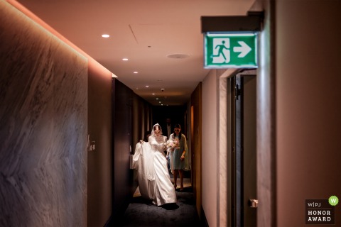 As the bride leaves her hotel room in Sardinia, the emergency exit sign becomes a playful detail in the frame, adding a touch of humor to this wedding day moment.