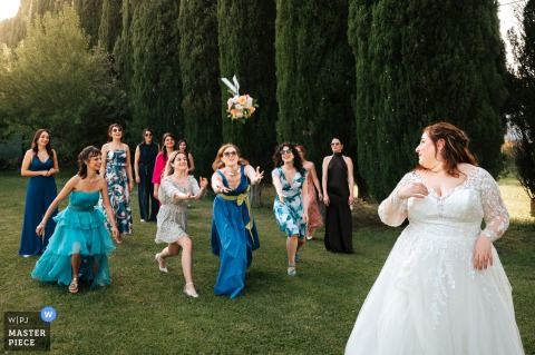 Excitement Fills The Air In Vitorchiano, Italy, As Guests Dash To Catch The Bouquet Thrown By The Bride. At Villa Giulia in Vitorchiano, Italy, the bride turns to watch as guests dash to catch the bouquet she has just thrown, anticipation and excitement filling the air among the hopeful crowd.