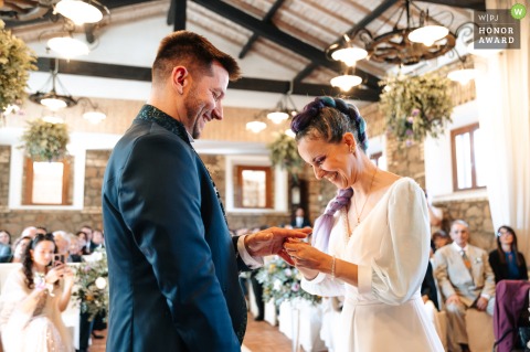 During the ceremony at Borgo Colle Mentuccia in Roma, the bride, dressed as a video game character, laughs as she slips the wedding ring onto the groom's finger.