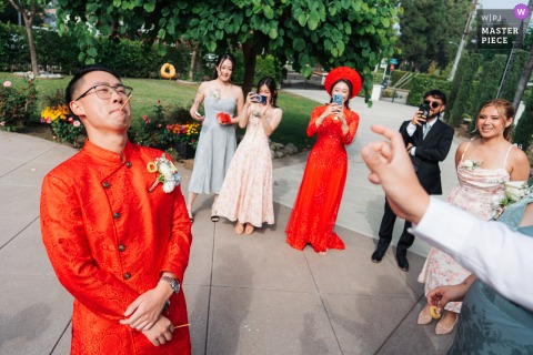   At a private house in Los Angeles, California, the groom enjoys a playful ring toss game with his bridal party following a traditional Vietnamese tea ceremony, celebrating with laughter and lively competition.