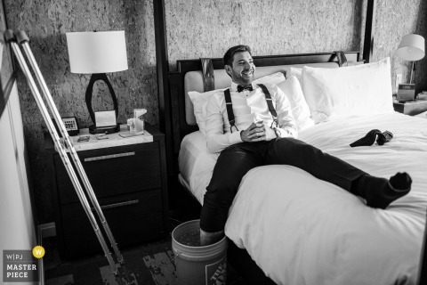 Nursing His Injured Foot, The Groom In Boulder, Colorado, Bravely Attempts To Fit Into His Shoes Before Ceremony. At St. Julien Hotel in Boulder, Colorado, the groom cools his broken ankle in a bucket of ice, making an effort to fit his injured foot into his wedding shoes for the ceremony.