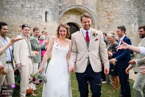 At Château De Mauriac, The Newlyweds Make A Grand Exit, Embarking On Their New Life Together In A Historic Venue. At Château de Mauriac, the bride and groom make a grand exit as they leave the ceremony, embarking on their new life together in the beautiful historic venue setting.