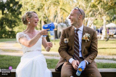   At Ferme d'En Chon, the bride and groom embrace fun and playfulness by enthusiastically playing with bubble guns, creating a lighthearted atmosphere at their wedding celebration.