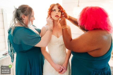 At Edwards Mansion in Redlands, California, two bridesmaids assist the bride with her earrings, sharing a quiet, heartfelt moment before the ceremony.