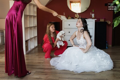 A bridesmaid gently fans the bride at her house on the morning of the wedding, offering comfort and support before the festivities.