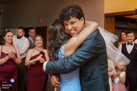   During the wedding reception, a man gleefully rejoices after catching a bow tie while embracing his girlfriend, their laughter echoing throughout the vibrant celebration at the Malopolskie reception venue.