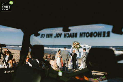 A beachfront wedding ceremony unfolds in Delaware, USA, with the gentle sound of waves providing a natural backdrop for the vows.