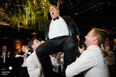   At Morgan Manufacturing in Chicago, IL, the father of the bride makes a hilarious face during the lively hora, creating a joyous and comical memory at the wedding reception.