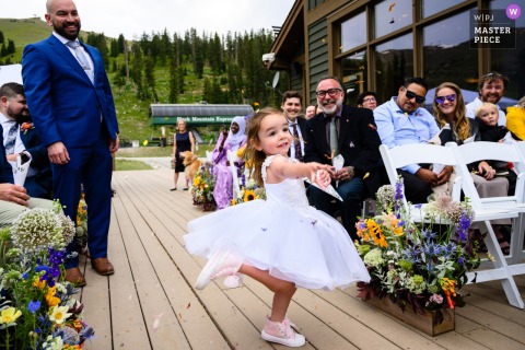   At Black Mountain Lodge, Arapahoe Basin Ski Resort in Colorado, a flower girl joyfully tosses petals as she walks down the aisle during the beautiful wedding ceremony.