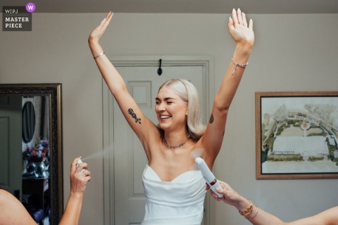 In The Walled Garden in Nottingham, UK, the bride is fanned and sprayed to cool down, a candid reminder that wedding elegance often depends on sweat and improvisation.