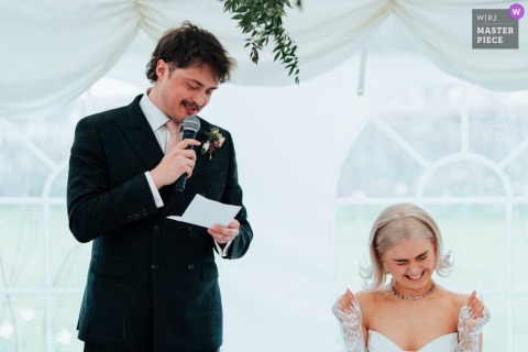 In The Walled Garden in Nottingham, UK, the bride reacts with joy to the groom’s speech, her expression opening the room with warmth, surprise, and gratitude.