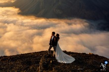 The bride and groom gaze at the sun's rays beaming through the clouds as they take in the heavenly view of Banff National Park, Alberta, Canada