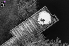 Love Afloat: A Breathtaking Aerial View of the Bride and Groom on Saint-Ybard Lake Dock The bride and groom stand together on a dock at Saint-Ybard lake, captured from a breathtaking aerial view provided by a drone
