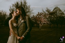 At Domaine des Gaillardoux in Lot, France, the bride and groom kiss in soft afternoon light, framed off-center with trees in the background.