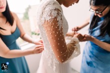 Bride’s friends adjust her dress, fixing buttons on back and sleeves at Seattle Airbnb wedding.