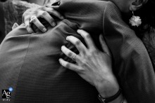 Black and White Poitiers Wedding: Groom's Powerful Embrace with Guest A powerful embrace between the groom and a guest, captured in a black and white shot at the ceremony location in Poitiers, Vienne, France.
