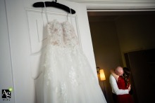 An elegant wedding dress hangs in a beautifully lit space in Hesse, Germany, showcasing the intricate lace details and delicate fabric before the bride begins her wedding day preparations.