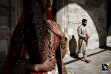 Pakistani bride's hands and dress details in shadow, with the groom in full sunlight behind her at Sultanahmet Mosque, Istanbul.