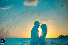 Couple’s silhouette at sunset contrasts beautifully with vibrant blue Tahiti water in Moorea, French Polynesia.