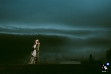 Bride and groom kiss passionately at Chateau des Gaillardoux, dramatic storm clouds gathering behind them.