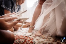 Bride in Vicenza softly puts on wedding shoes, bridesmaids assisting lovingly, anticipation and grace evident.