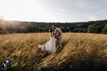 The married couple kissing in a field of tall, dry grass at Chateau de Mazieres, their wedding venue.