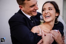 Newlyweds laughing together during wedding portraits at Clay Venues, Colorado Springs, CO, as he wraps her up from behind.