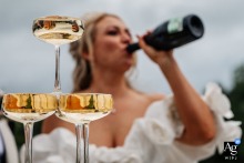 An unusual shot of the bride enjoying champagne from the bottle, mirrored within champagne glasses at Crow Wood Hotel, Lancashire.