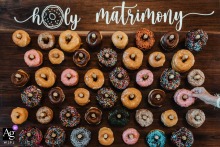 The Venue at Turkey Ridge, Shelby NC, features a close-up detail shot of a wedding day dessert where a grandmother's hand delicately reaches to grab a donut labeled "Holy Matrimony" from an artfully arranged display.