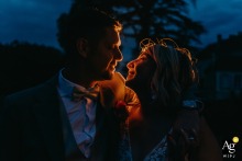 Château de Contremoret — The couple faces each other, smiling and embracing during a nighttime kiss, softly illuminated by a warm glow close to and behind them, creating a romantic and intimate wedding portrait.