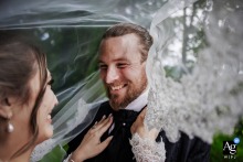 Le Grand Hotel, Le Pont, Switzerland — The bride and groom laugh together as her veil envelops his face and smile, creating a joyful and intimate wedding day portrait during their Swiss celebration.