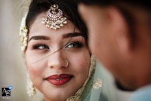 Blue Mosque, Istanbul, Türkiye — In a tight wedding day portrait, the bride gazes at the groom while wearing traditional attire and jewelry, her face softly illuminated.