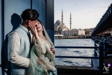 Galata Bridge, Karakoy, Istanbul — The couple poses for a wedding day portrait on the dark blue-painted bridge, dramatically lit by the photographer’s off-camera flash against the city and water backdrop.