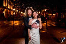 A Romantic Urban Embrace: Rainy Night Wedding Portrait, Arlington, Virginia Arlington, VA — The groom embraces the bride in the rain on urban streets near the reception venue, dramatically lit by the photographer to create a romantic and atmospheric wedding portrait.
