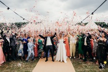 At Worcester Lodge Badminton Estate Wedding Party Group Portrait as Confetti is Thrown Worcester Lodge, Badminton Estate — The entire wedding party gathers for a group portrait as confetti is thrown high, capturing a joyful and well-executed image with everyone together in front of the historic estate.