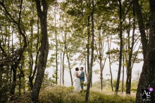 Monts du Lyonnais Couple Stands Low Framed by Tall Trees in Forest Portrait Monts du Lyonnais — In a minimalist wedding portrait, the couple stands low in the frame, surrounded and framed by tall trees in the middle of the forest, highlighting the serene natural setting.