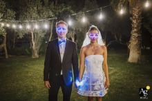Bodrum Flamm — The couple poses for a nighttime portrait under trees before the after party, both wearing playful glow stick glasses, creating a fun and artistic atmosphere at their wedding celebration.