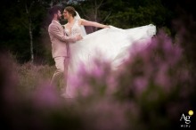 Rucphense Heide, Rucphen — The couple embraces among the purple moor flowers, with the bride playfully tossing her dress to the side, creating a vibrant and romantic wedding portrait in the natural setting.