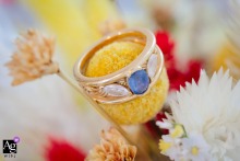 The bride's sparkling engagement ring is delicately placed among the fresh blooms of her wedding bouquet, creating an intimate and artistic detail captured on her special day in L'Isle d'Abeau, France.