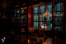 The Loft at Lena’s, Alexandria, VA — The couple share an intimate gaze during a pre-dinner portrait, seated together at a table near tall windows, with soft indoor lighting highlighting their connection in the restaurant setting.