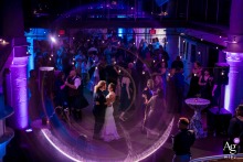 Torpedo Factory, Old Town Alexandria, VA, Reception Venue — During their first dance, the couple invite all wedding guests to join them, while a high-angle shot, creative in-camera effect, and dramatic backlight isolate them under purple lighting ambiance