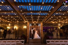   At Baldoria on the Water in Lakewood, Colorado, the newlyweds dance together under a dramatic sunset sky, with bold lighting enhancing the romantic scene.