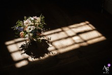   At Tunnels Beaches in Devon, UK, sunlight streams through a window, softly illuminating a floral arrangement and adding natural beauty to the celebration’s decor.
