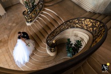   In Nancy, France, the bride and groom share a peaceful moment at the base of a monumental staircase, the sweeping architecture lending elegance to their portrait.