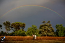   In a picturesque field below a rainbow and stormy skies at Château Destinée, France, the groom carries the bride, the vibrant scenery adding a sense of wonder to their portrait.