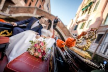   In Venice, Italy, a close-up of an ornate gondola detail beautifully frames the couple sharing a kiss, softly blurred in the background along the iconic canals.