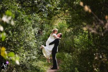   Within the park’s lush landscape, the couple stops for a portrait, the foliage and soft lighting setting a tranquil tone for their wedding photograph.