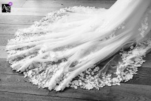 At Château d'Arcelot in France, the bride's wedding dress train is photographed in black and white, emphasizing its flowing lines, rich texture, and timeless elegance through a refined detail image.
